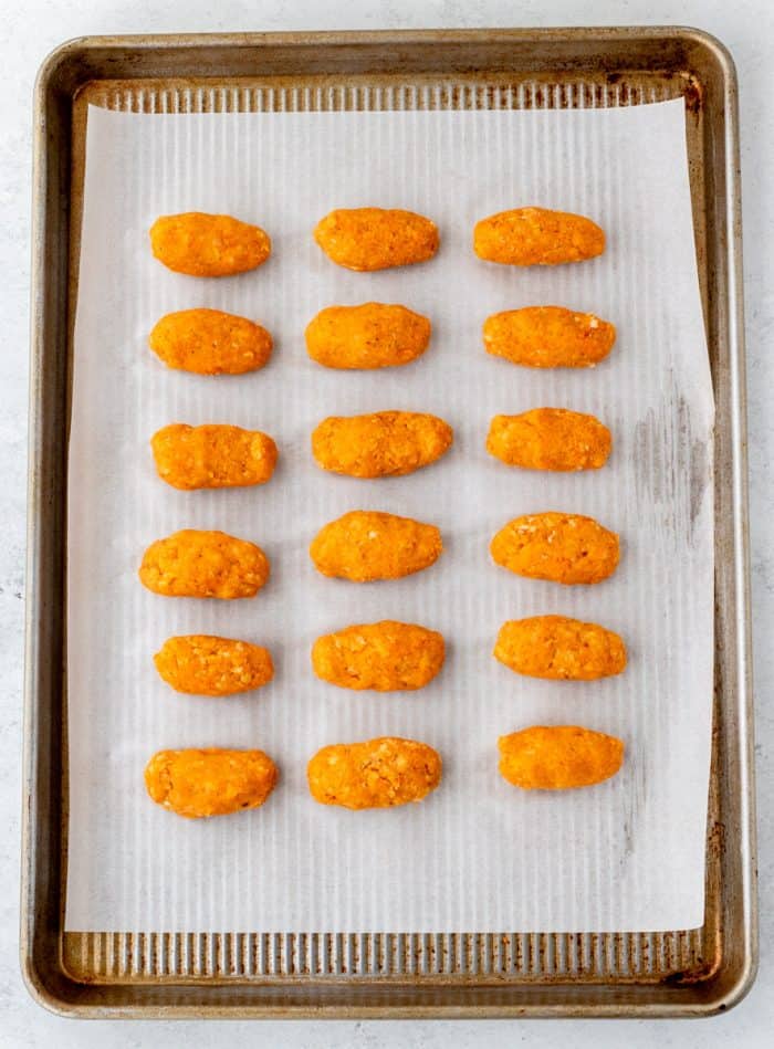Uncooked sweet potato tots on a lined baking sheet.