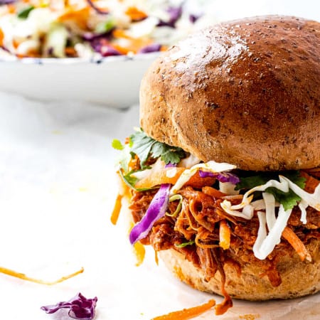 Pulled pork on a bun with coleslaw in a bowl