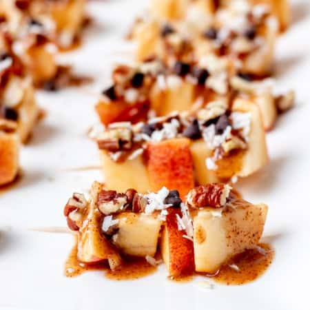 Apple skewers drizzled with caramel sauce and chopped nuts.