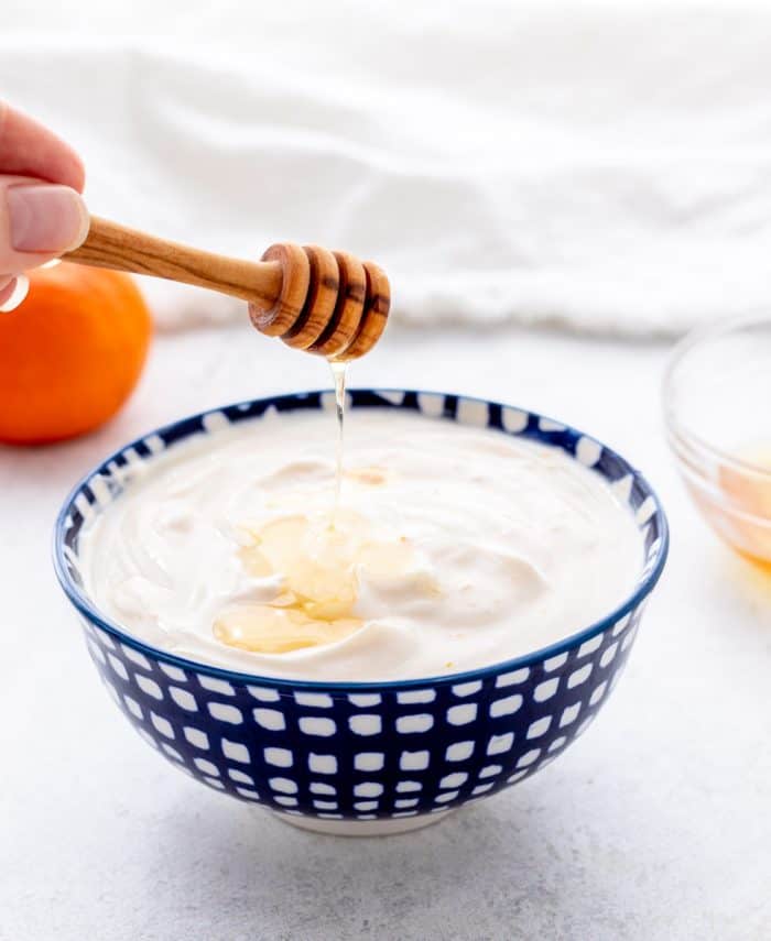 Drizzling honey into a bowl of yogurt