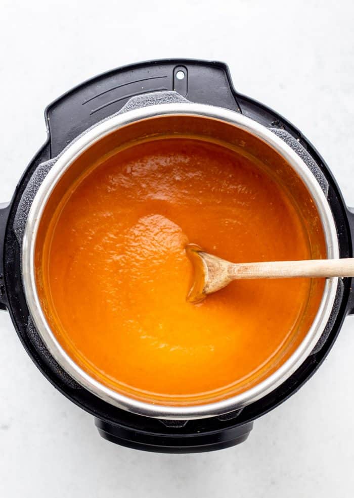 Pumpkin soup in the Instant Pot with a wooden spoon.