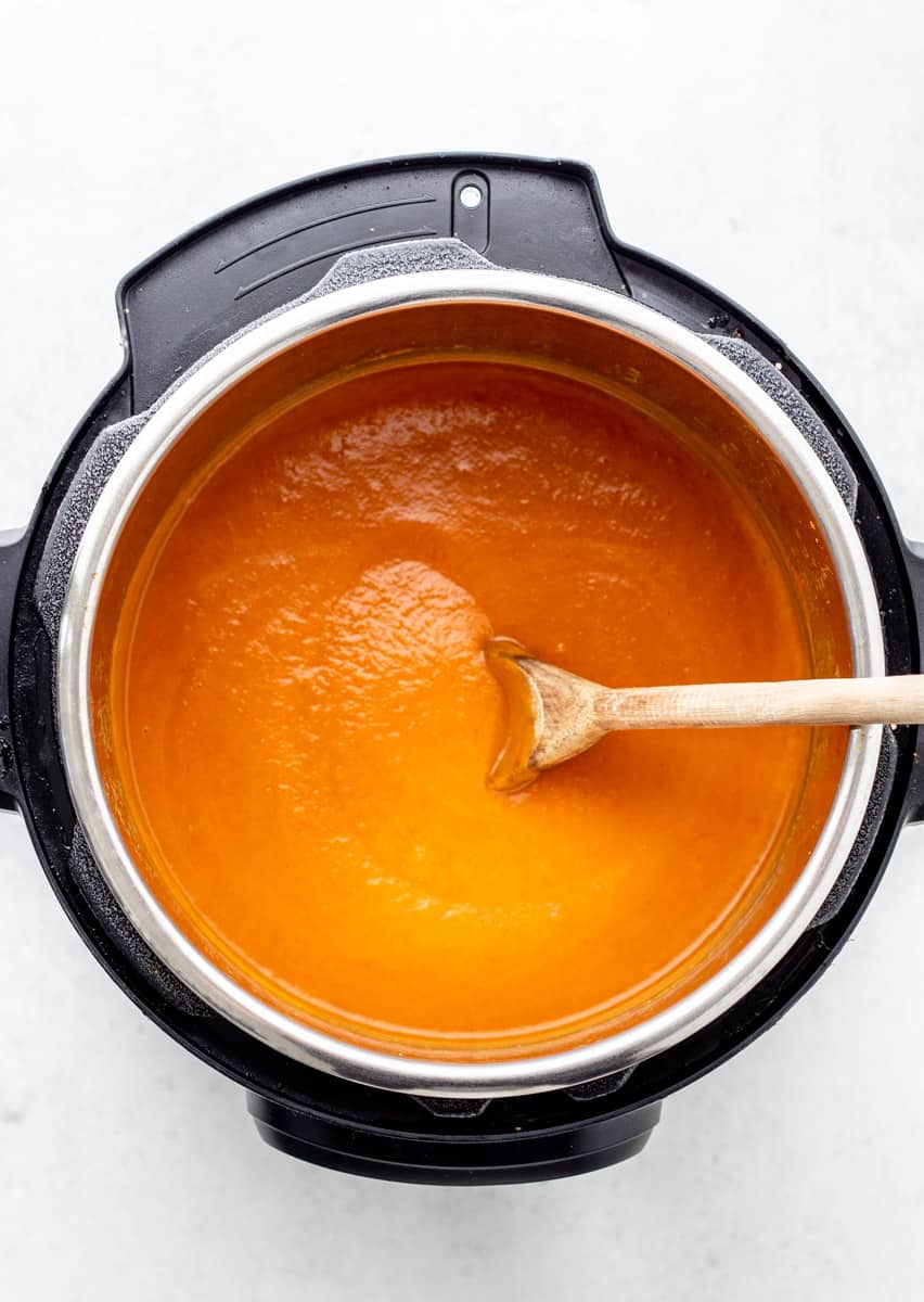 Pumpkin soup in the Instant Pot with a wooden spoon.