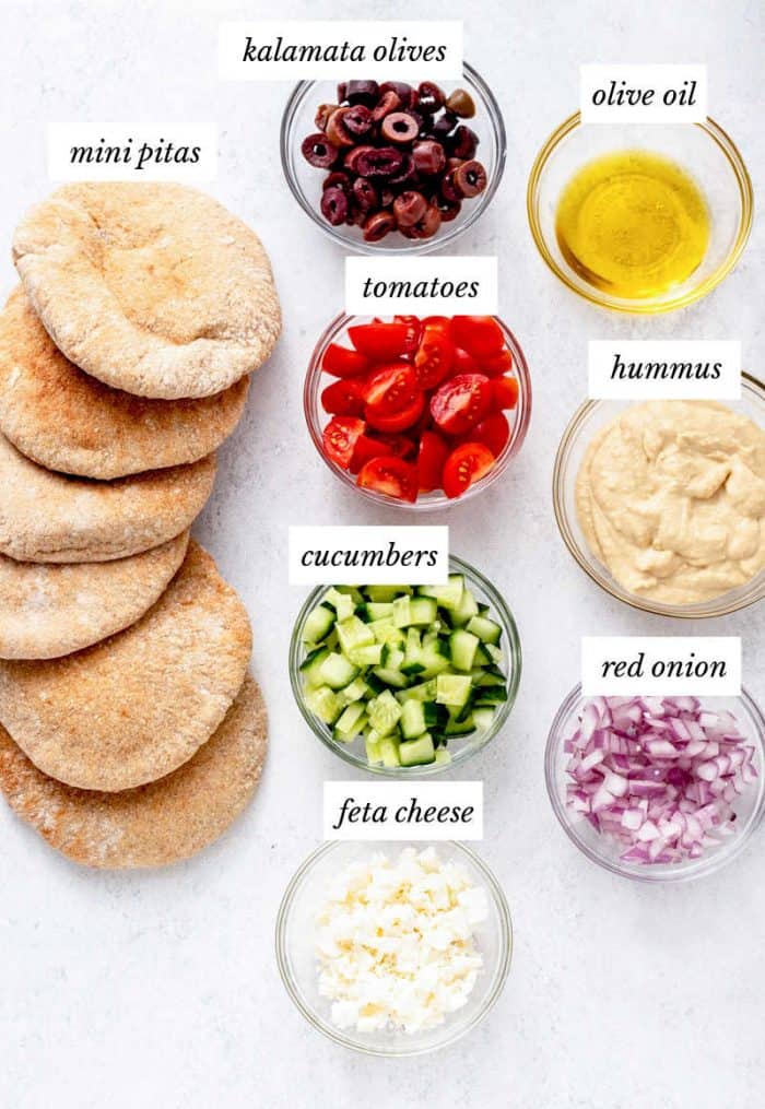 Ingredients for pita pizzas on grey background with labels