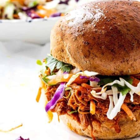 Pulled pork on a bun with coleslaw in a bowl