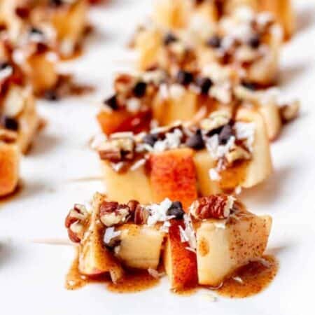 Apple skewers drizzled with caramel sauce and chopped nuts.