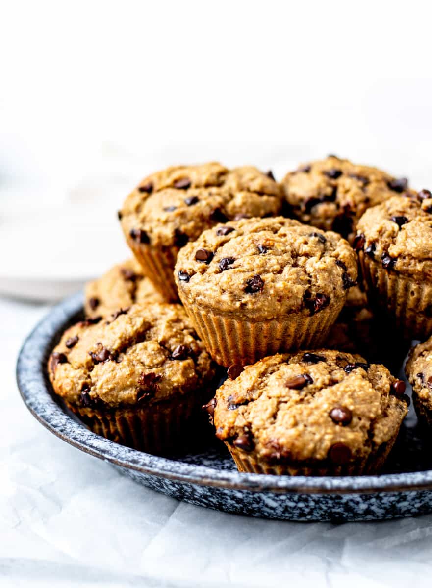Protein powder muffins with chocolate chips stacked on top of each other on a plate.