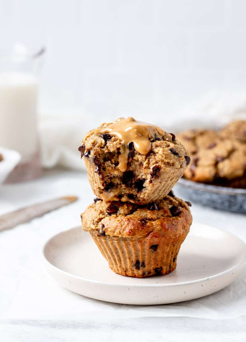 Two chocolate chip protein muffins stacked on top of each other with drizzle of peanut butter.