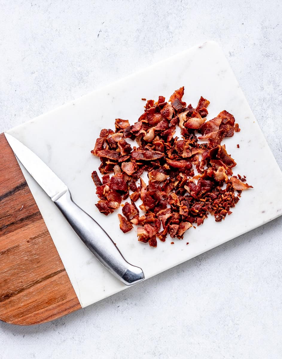 chopped up bacon on a cutting board next to a knife