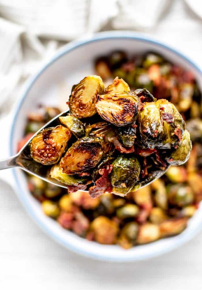 holding up big spoon with brussel sprouts and bacon