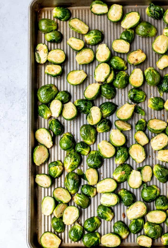 Halved brussel sprouts on a baking sheet with a maple balsamic glaze