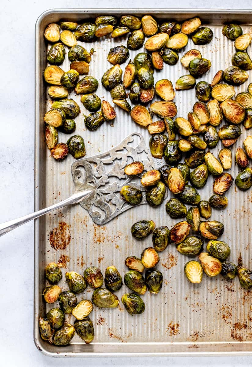 roasted brussel sprouts on a baking sheet with silver spatula