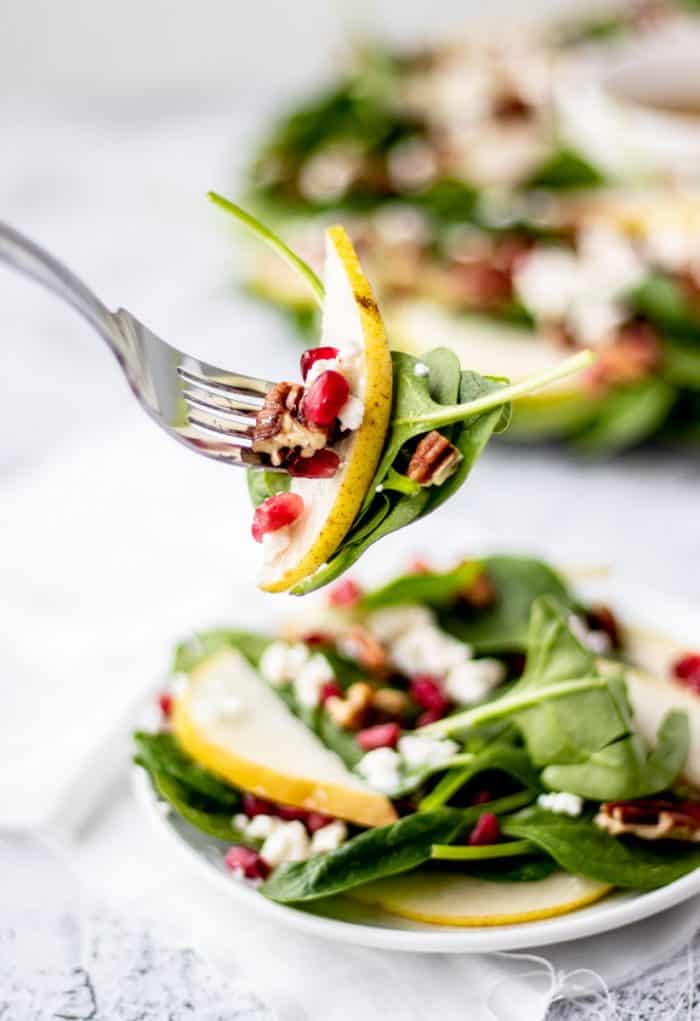 a fork holding up some of the pomegranate and pear salad