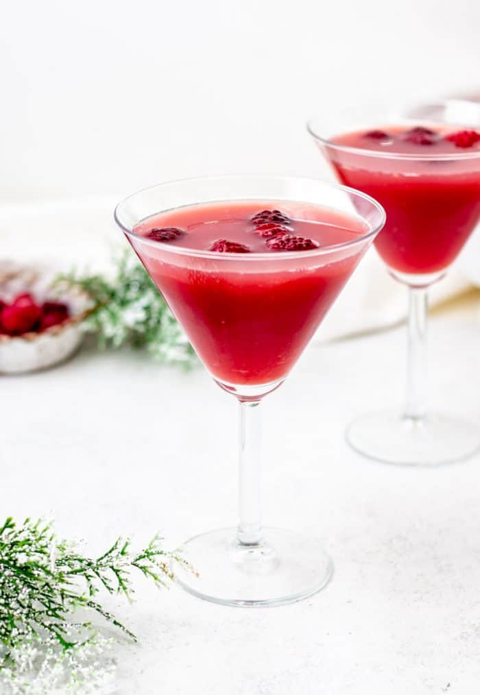 two glasses of christmas punch with raspberries floating in it