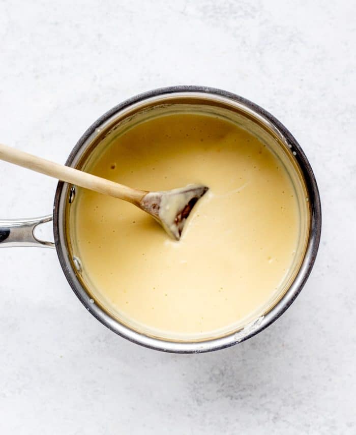 custard cooking in a pot with a wooden spoon