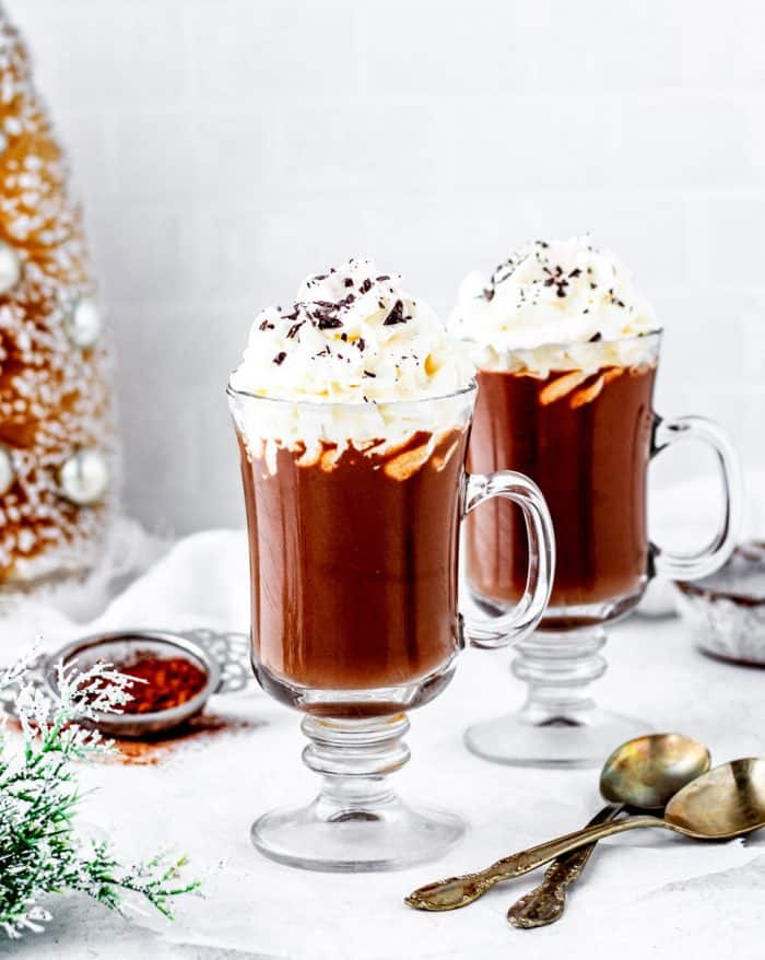 Two mugs of healthy hot chocolate topped with whipped cream.