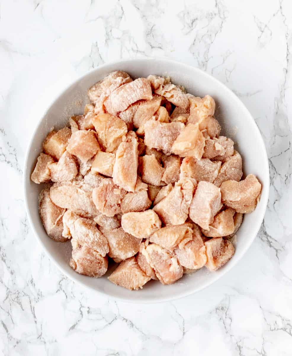 chicken pieces coated in flour in a white bowl