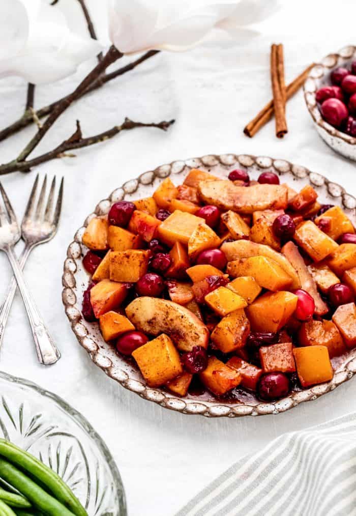 Butternut squash casserole with apples and cranberries on plate next to two forks