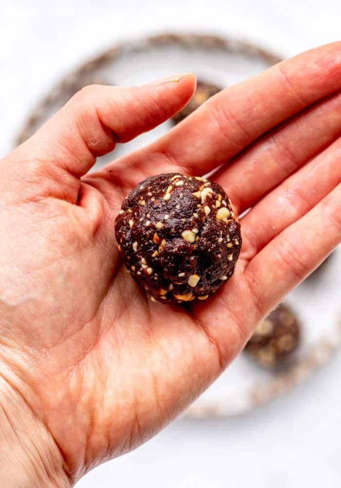 a hand holding a chocolate energy ball close to the camera