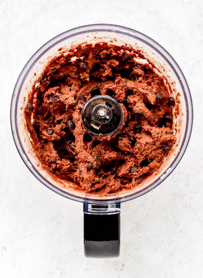 chocolate chickpea brownie batter in a food processor with chocolate chips added.