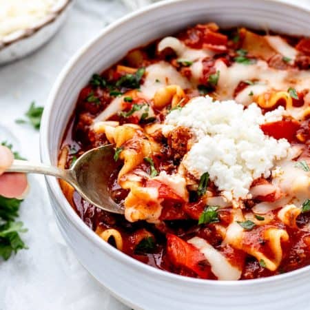 Lazy lasagna soup served in a white bowl with cheese toppings.