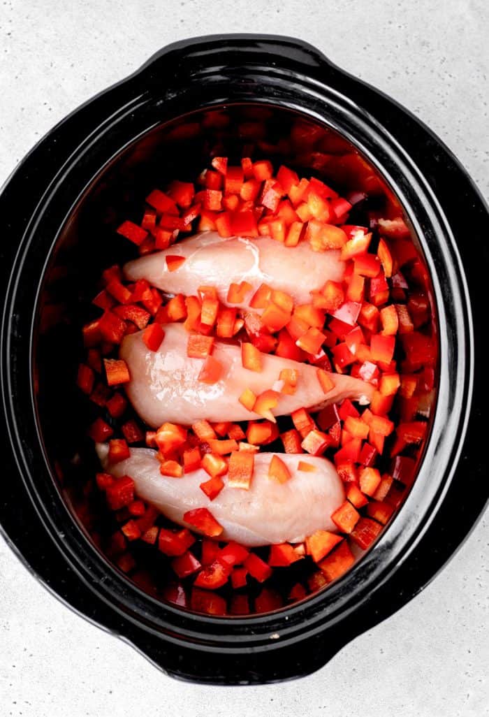 Chicken breasts, bell pepper and sauce in a slow cooker.