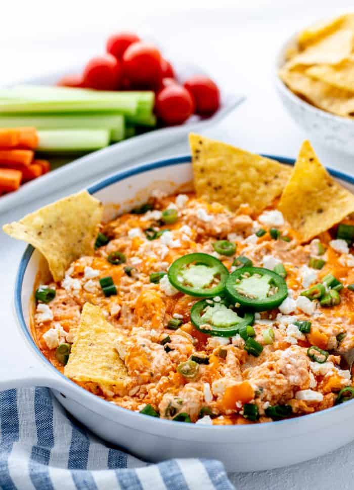 Chips dipped into a serving dish with Greek yogurt buffalo chicken dip.