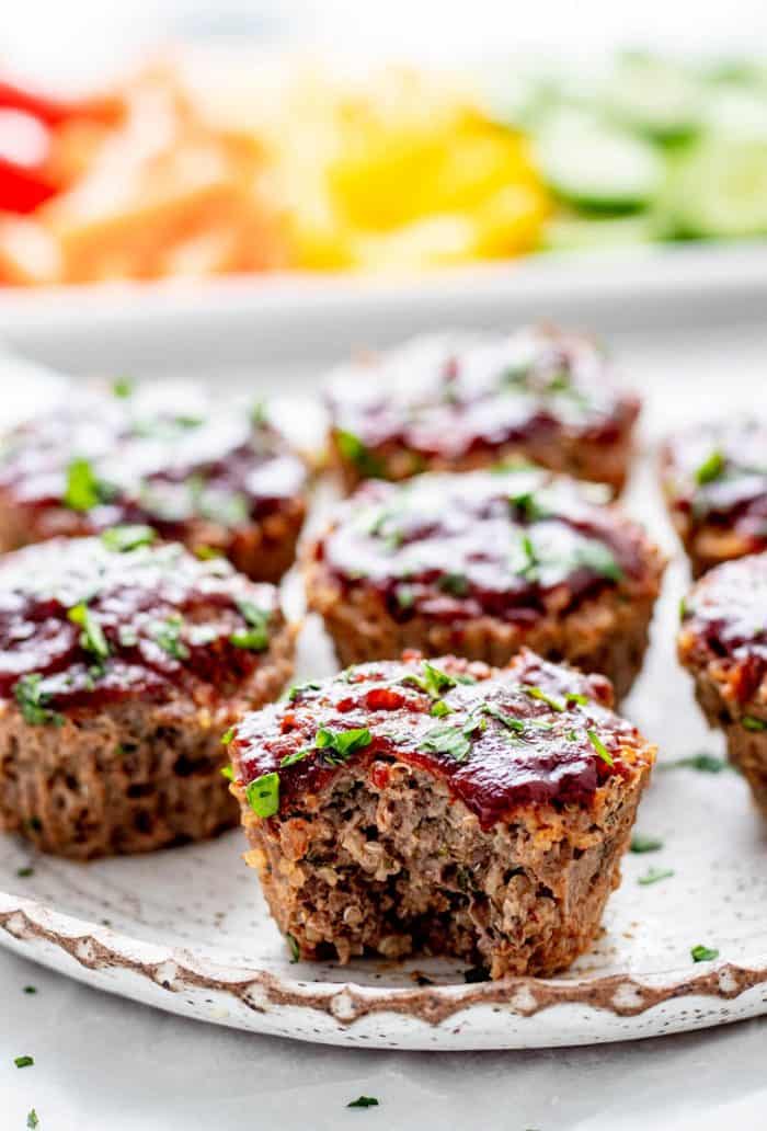 Beef and quinoa baby meatloaf muffins on a plate topped with BBQ sauce.