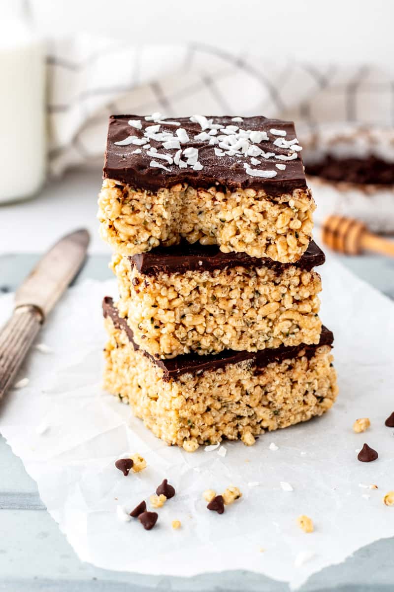 Three chocolate rice krispie treats stacked on top of each other with a bite taken out of top bar.
