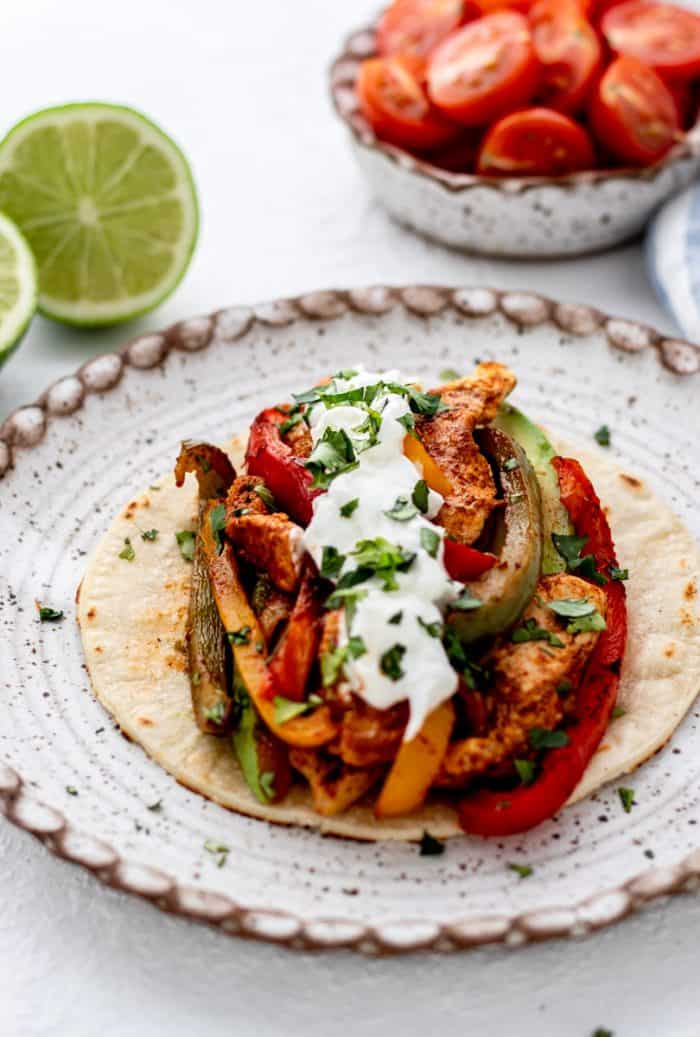 Mexican chicken fajitas served on a tortilla and topped with sour cream and cilantro.