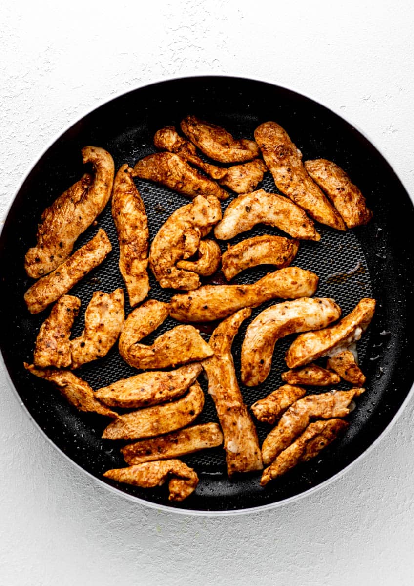 Cooked chicken strips in a cast iron skillet.