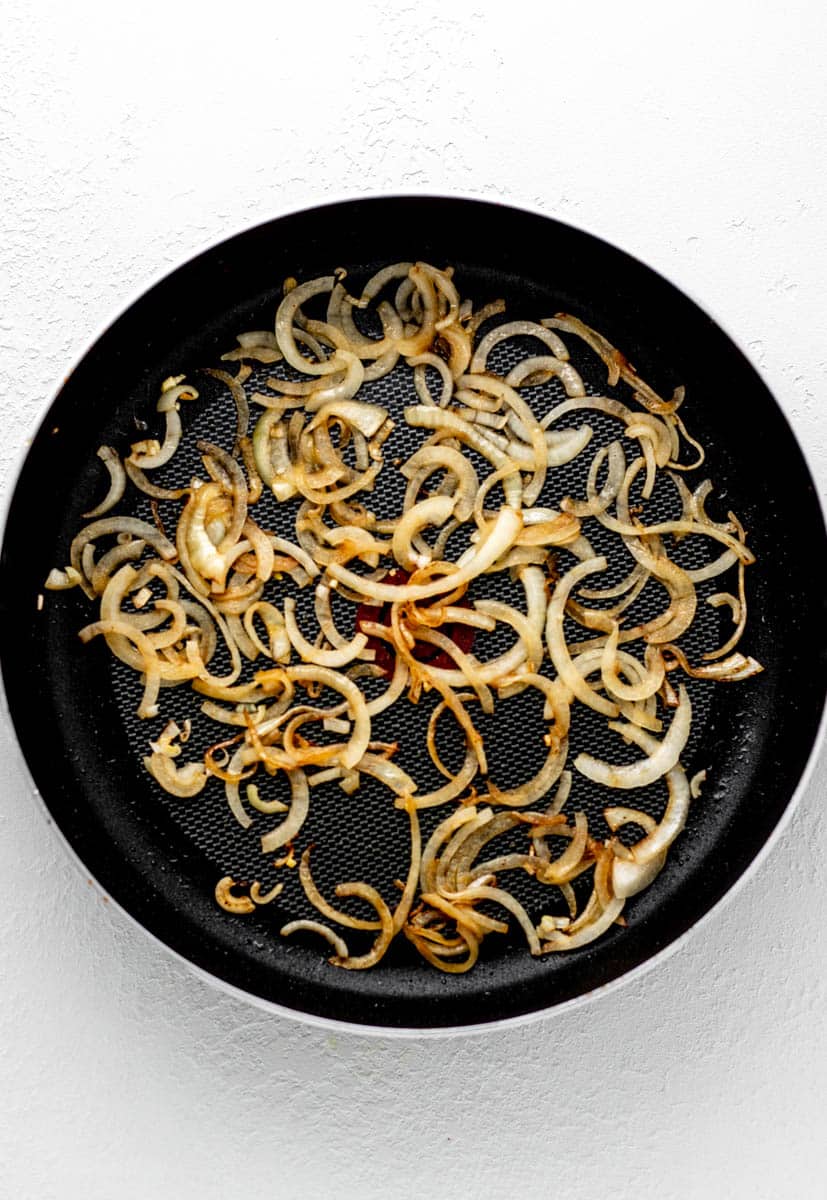 Sliced onions cooked in a skillet.