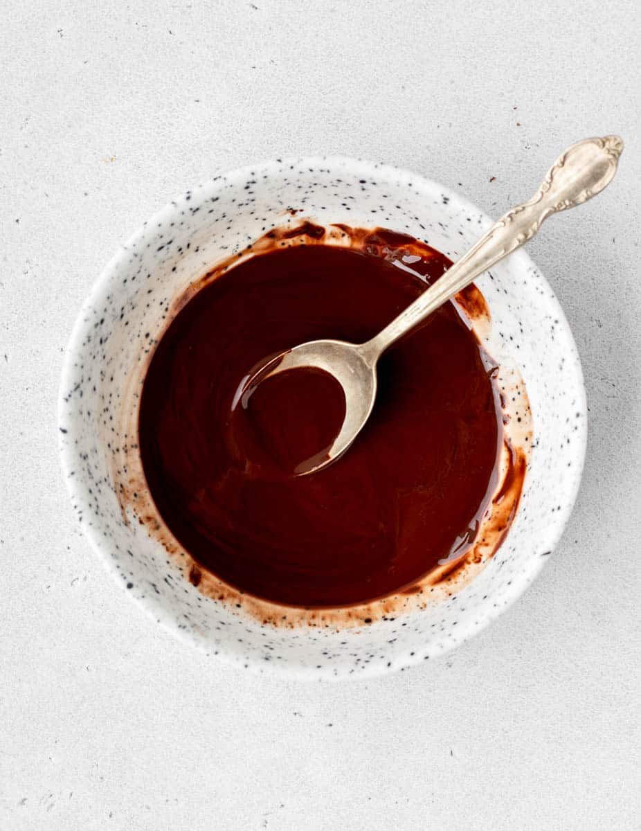 Chocolate glaze in a bowl with a spoon.