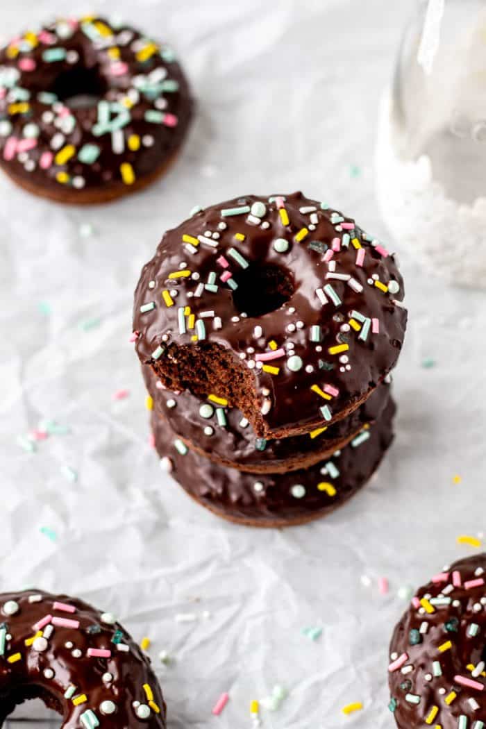 Three donuts stacked on top of each other with a bite taken out of one.