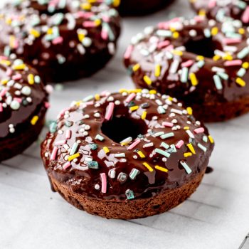 Chocolate glazed donuts topped with sprinkles.