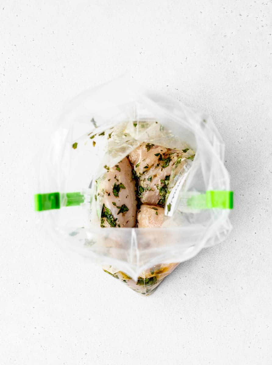 Cilantro lime marinade in a freezer bag with chicken on bag clips.