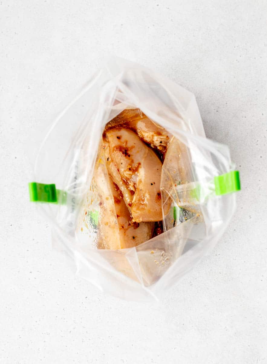 Lemon ginger marinade in a freezer bag with chicken on bag clips.