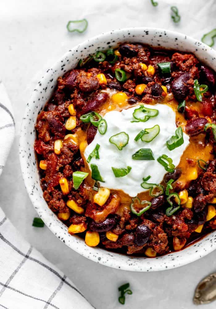 Kid-friendly chili in a bowl topped with cheese, yogurt and green onion.