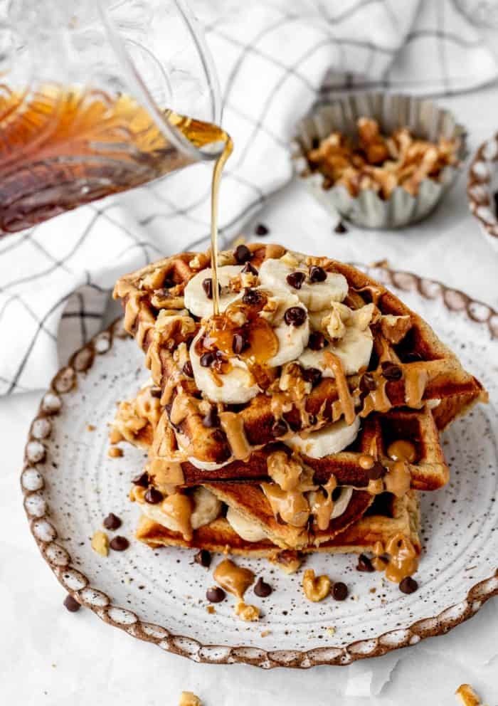 Maple syrup being drizzled over a stack of protein waffles.