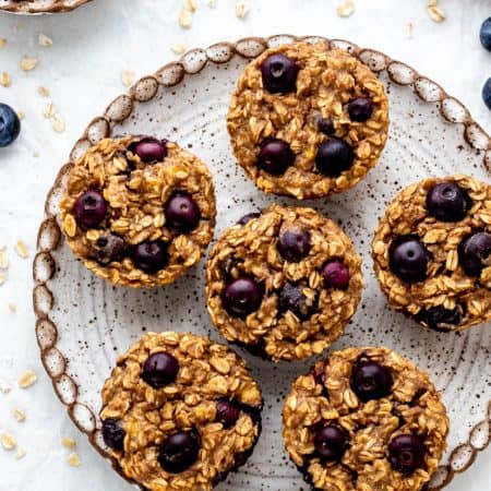 Six blueberry banana oatmeal muffins served on a plate.