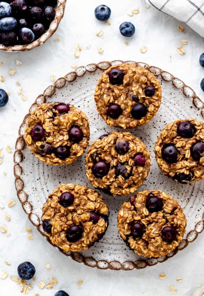 Six blueberry banana oatmeal muffins served on a plate.