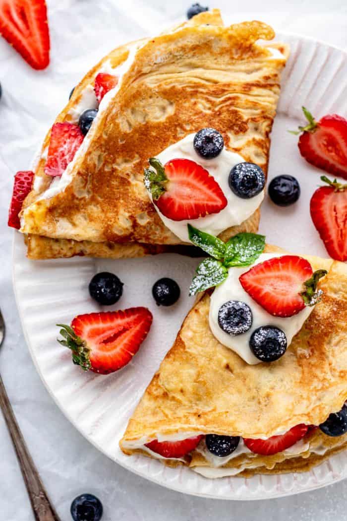 Two healthy crepes topped with fresh fruits and yogurt.