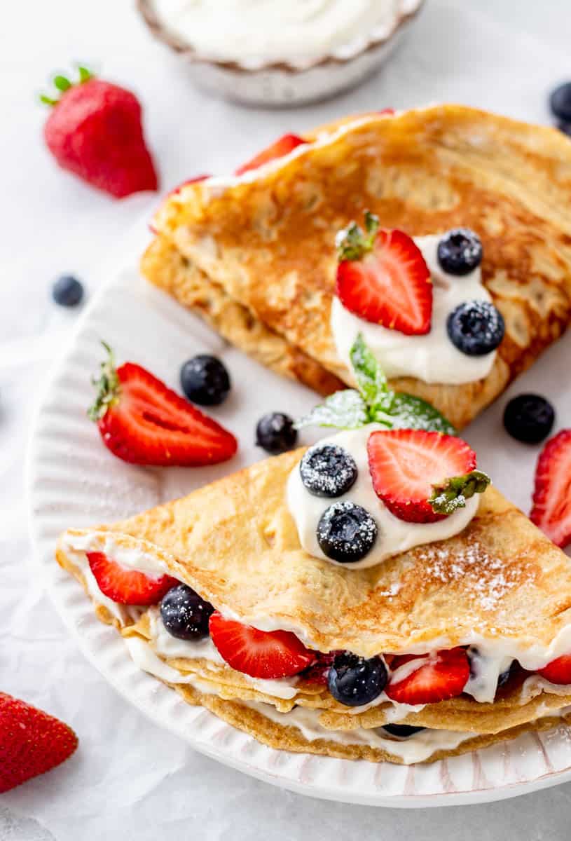 Crepes with filling and berries on a white plate.