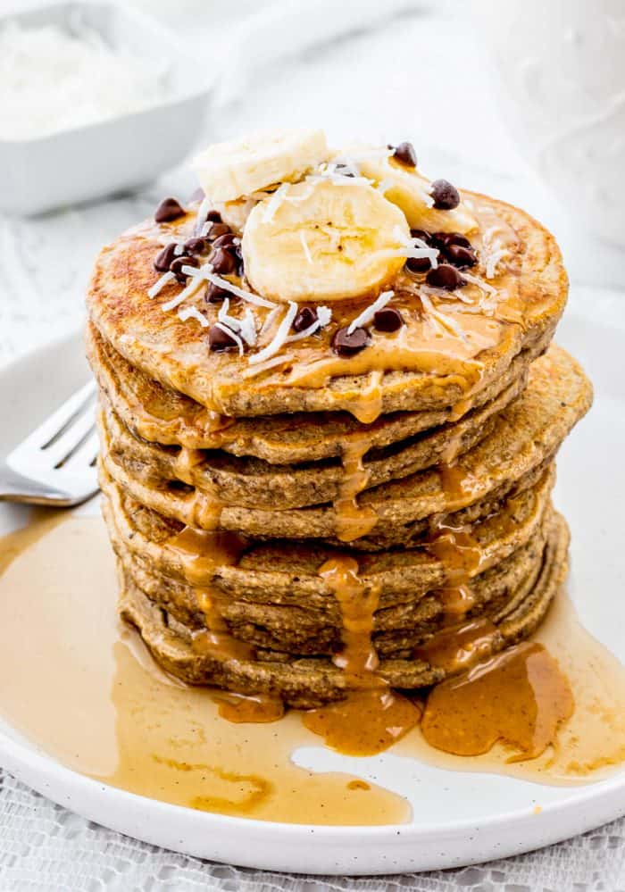 A stack of banana protein pancakes topped with bananas and chocolate chips.
