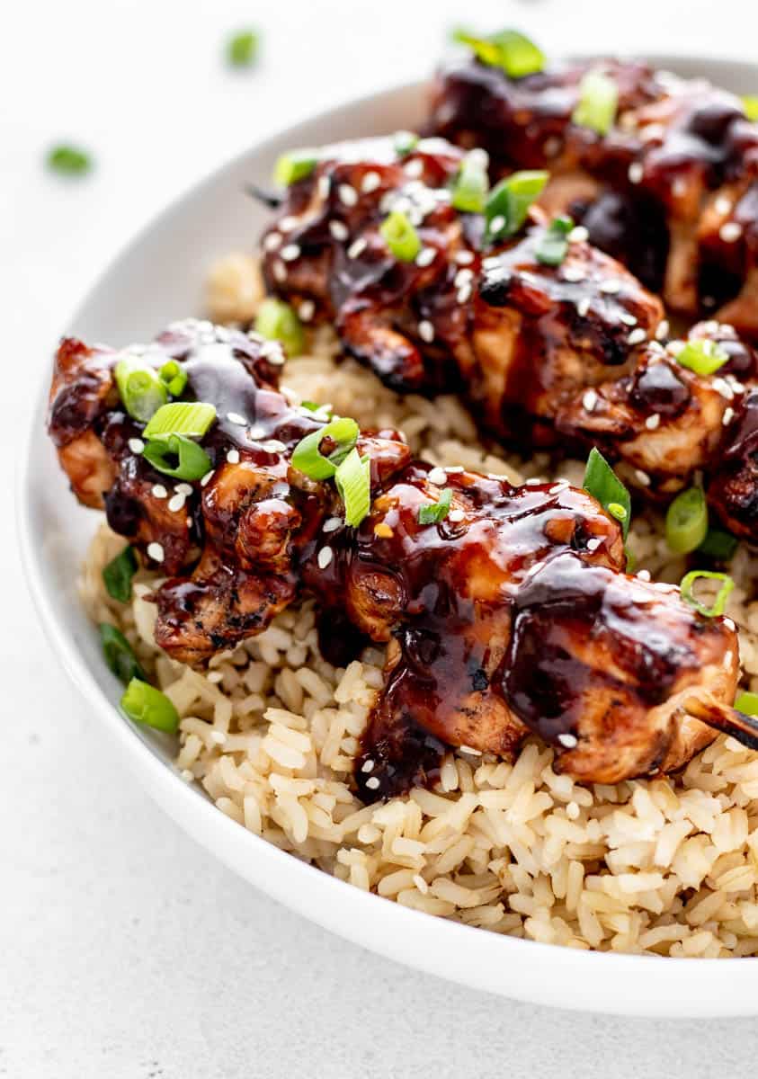 Teriyaki chicken on a stick over a bed of rice.