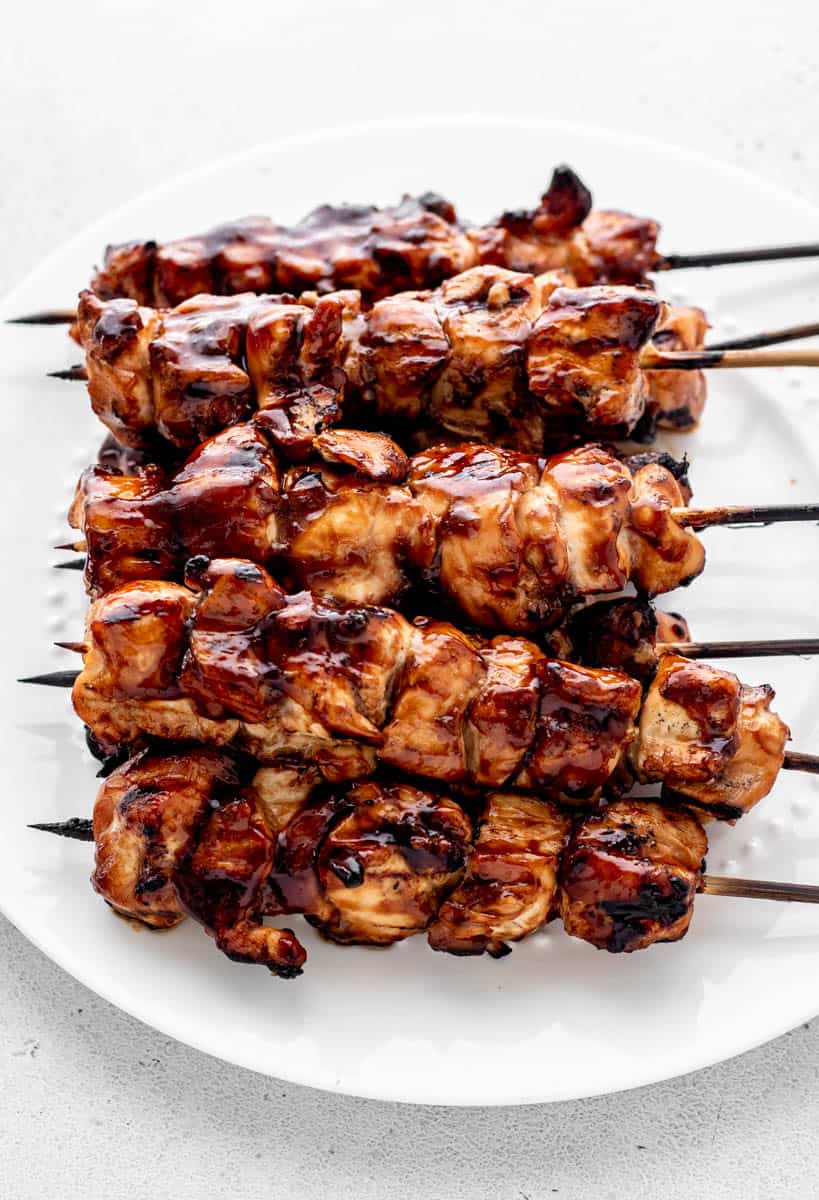 A plate of grilled teriyaki chicken on a stick.