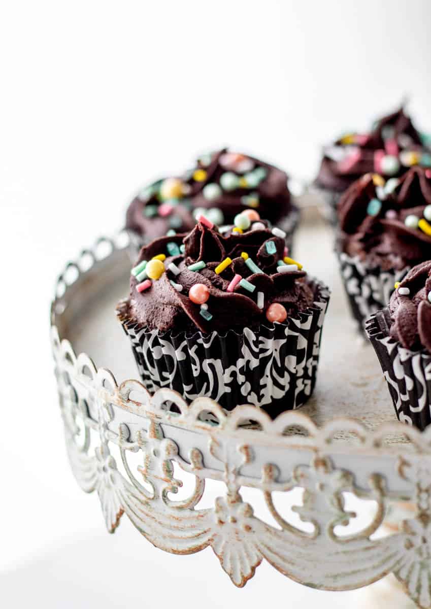Dairy free chocolate frosting piped on cupcakes with sprinkles.