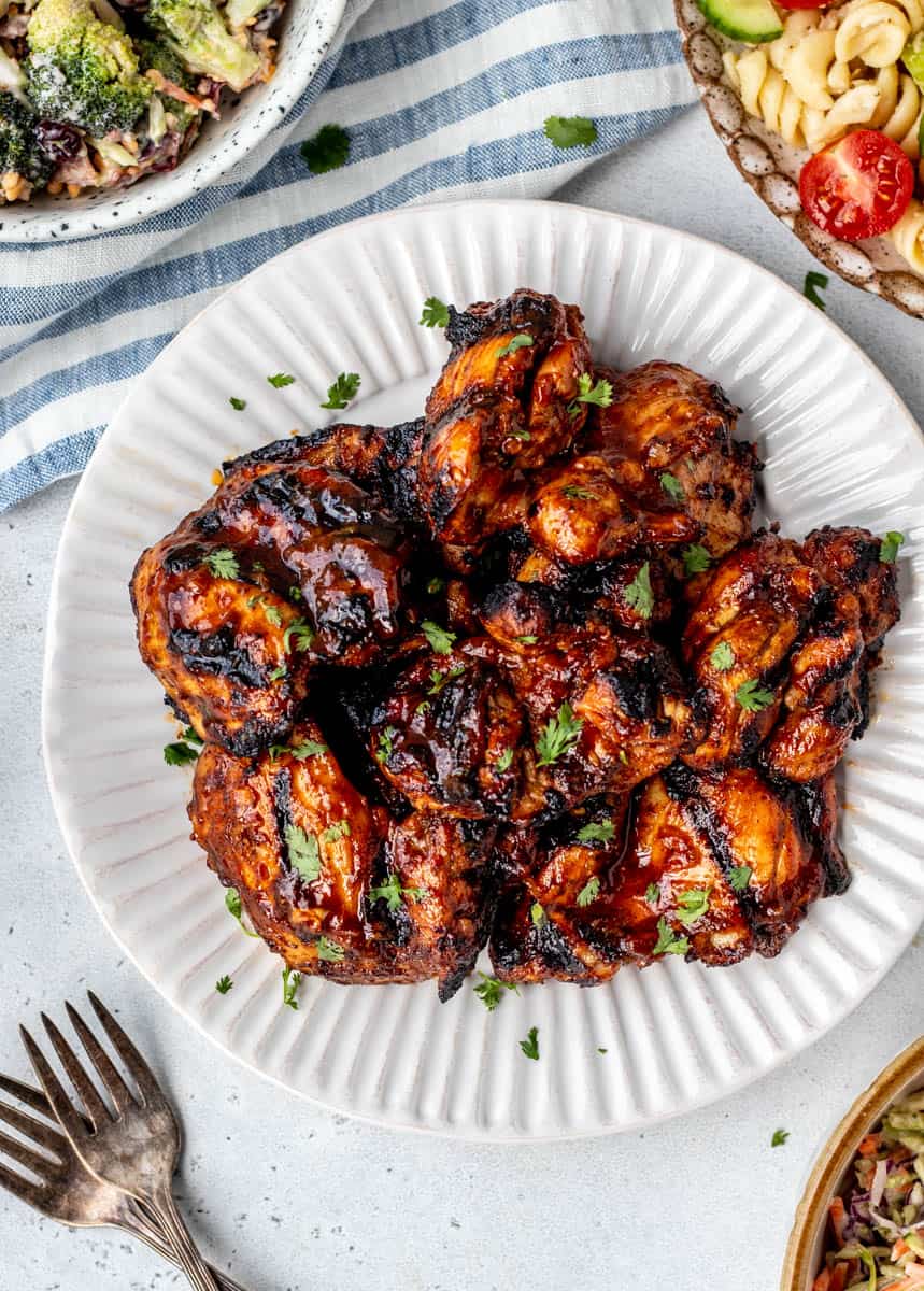 Grilled BBQ chicken thighs on a plate.