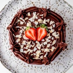 Overhead shot of flourless chocolate cake topped with strawberries and coconut flakes.