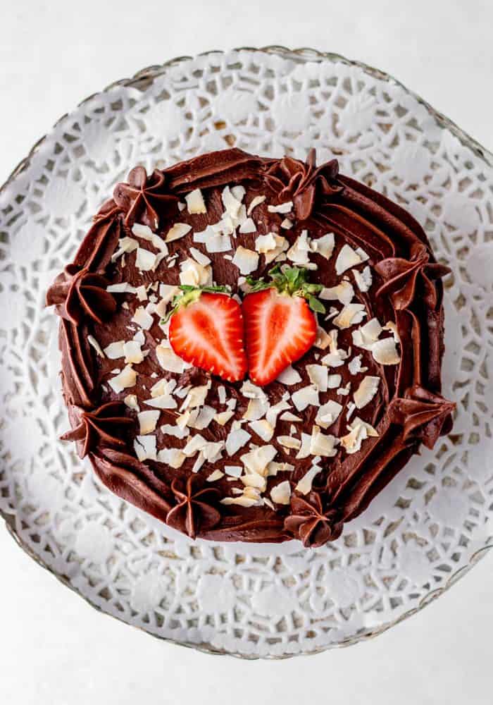 Overhead shot of flourless chocolate cake topped with strawberries and coconut flakes.