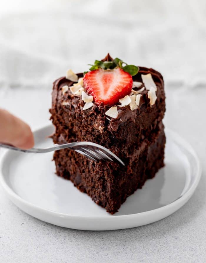 A fork poking into a slice of fudgy chocolate cake.